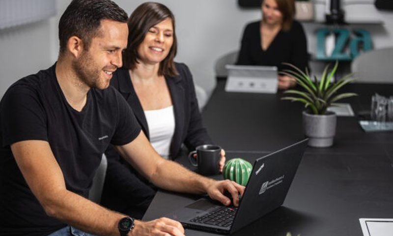 Zwei Personen, die gemeinsam auf einem Laptop arbeiten und die Buchhaltungssoftware von RZA für alle Branchen bedienen