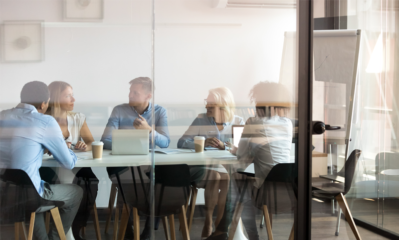 Mehrere Menschen in einem Büroraum, wo die Reports der Buchhaltung für eine GmbH besprochen werden