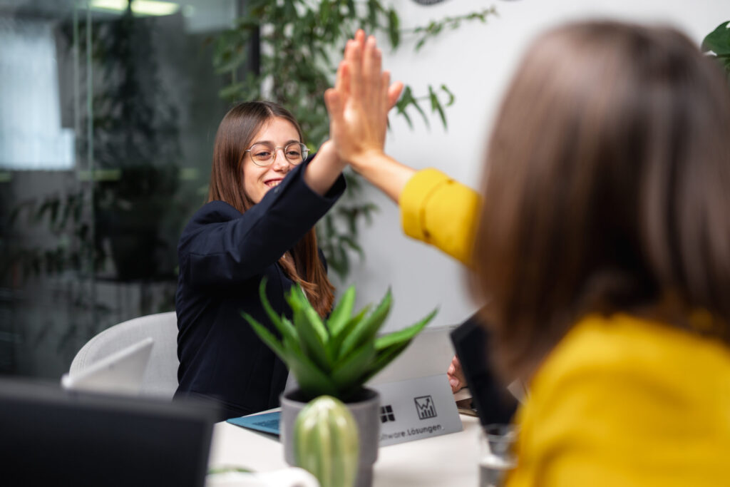 Zwei Kolleginnen klatschen ein weil sie eine optimale easy2000 Alternative für die Lohnverrechnungssoftware gefunden haben