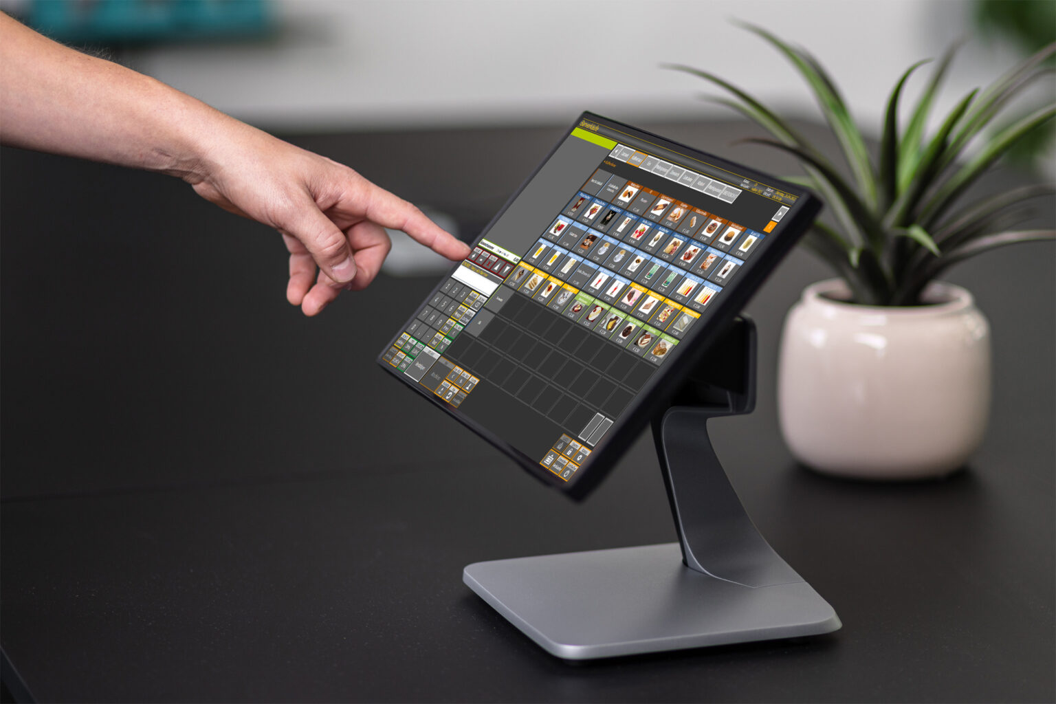 Eine Hand tippt auf ein Kassendisplay und bedient die neue Registrierkassensoftware.