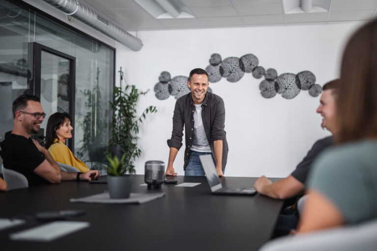 Mitarbeiter steht im Meeting beim Meetingtisch und erklärt, warum eine Software aus Österreich wichtig ist.